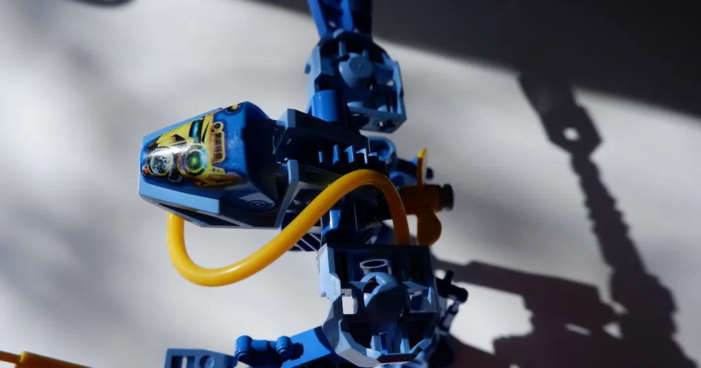 A photo of a person working on a laptop with a robotic arm in the background, symbolizing the intersection of human and artificial intelligence in the workplace