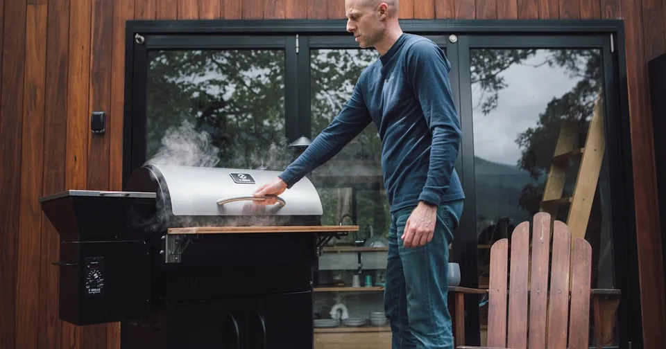 A sleek, modern outdoor pizza oven with a wood-fired interior, situated in a lush backyard