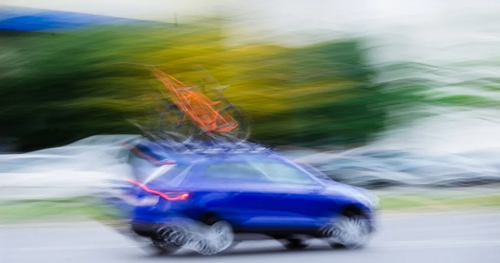 A photo of a Tesla vehicle with a robotic arm attached, symbolizing the fusion of human and artificial intelligence in autonomous driving